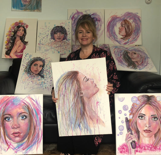 Artist Julie Hogarth-Jones seated with several brightly coloured portraits of women.