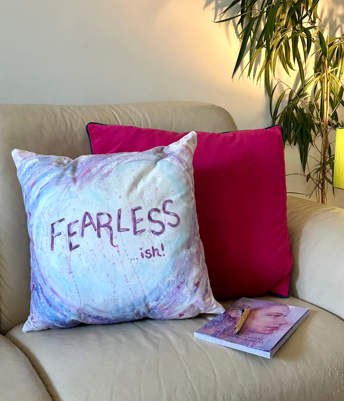 Fearless-ish cushion by Julie Hogarth-Jones in a styled corner sofa setting with plant and lamp.