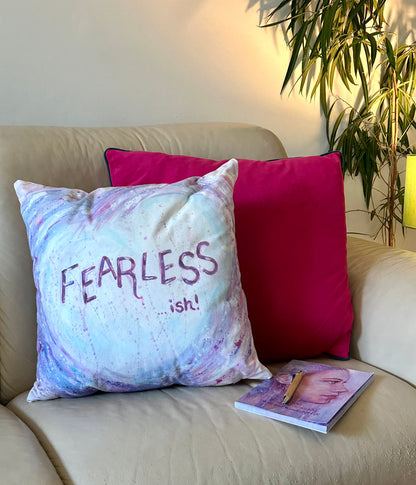Fearless-ish cushion by Julie Hogarth-Jones in a styled corner sofa setting with plant and lamp.