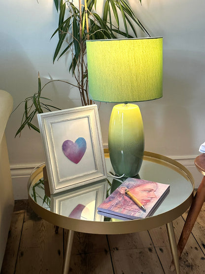 Hand-painted heart from the Into the Wild Rediscovery Box by Julie Hogarth-Jones, framed and styled on a glass coffee table with book, pen and lamp.