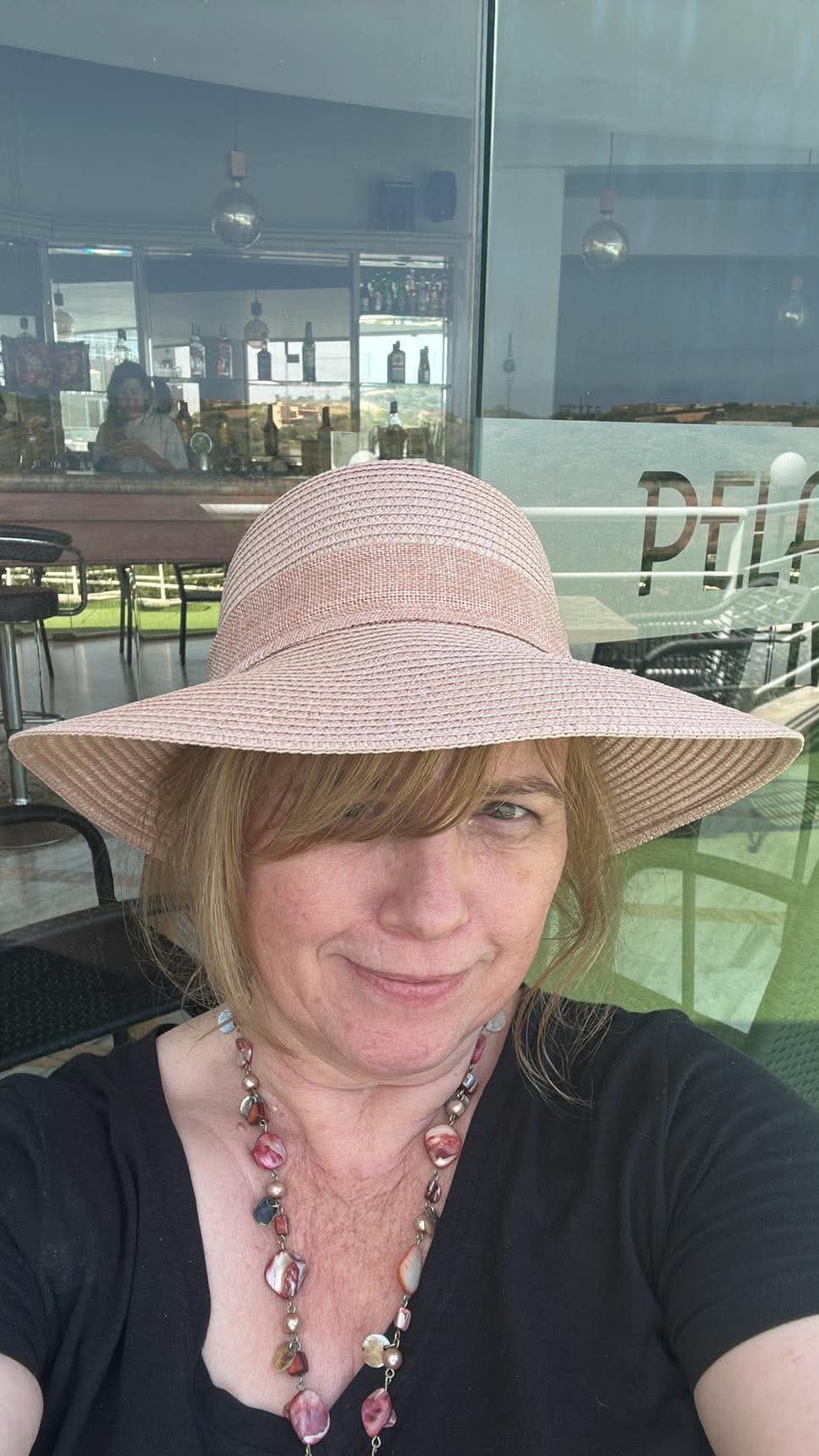 Julie Hogarth-Jones, Artist - smiling in a pink straw hat and black t-shirt.