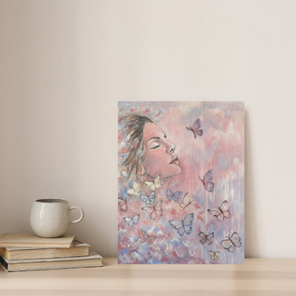 Metamorphosis canvas print of a woman with butterflies  by Julie Hgoarth-Jones displayed on a shelf in a styled home setting. 