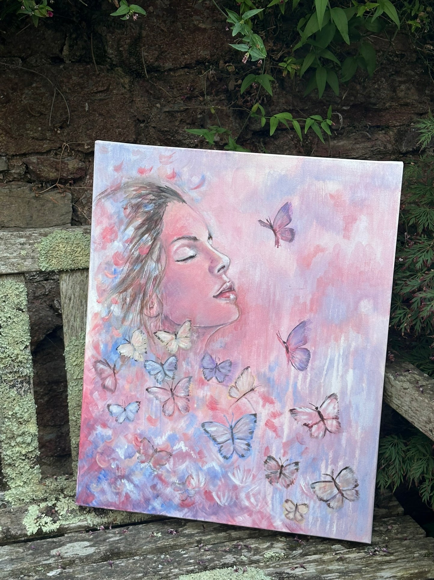 Metamorphosis - original painting by Julie Hogarth-Jones. Portrait of a woman surrounded by butterflies - styled on a bench outdoors. 